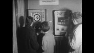 Drei Jugendliche stehen vor Spielautomaten.  