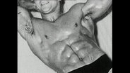 Ein Bodybuilder präsentiert seinen durchtrainierten Bauch.  