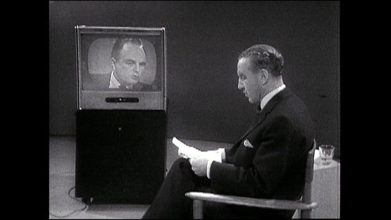 Mann sitzt auf einem Stuhl vor einem Fernseher (Archiv-Bild).  