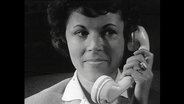 Frau hält sich einen Telefonhörer ans Ohr.  