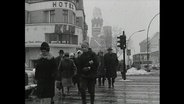 Menschen überqueren eine Straße in Berlin.  