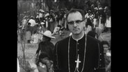 Priester vor einer Menschenmenge.  