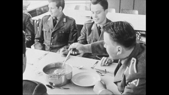 Soldaten sitzen am Tisch und essen Suppe.  