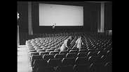 Zwei Menschen setzen sich ins leere Kino.  