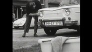 Ein Mann putzt die Scheinwerfer seines Autos (Archiv-Bild).  