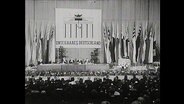 Ein voller Saal, zu sehen das Plakat mit der Aufschrift "Unteilbares Deutschland".  