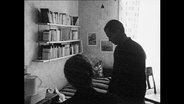 Ein Mann und eine Frau stehen in einem Studentenzimmer.  