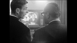 Zwei Männer schauen sich im Fernsehen die Nachrichten an.  