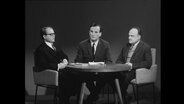 Drei Männer sitzen um einen Tisch und diskutieren (Archivbild)  