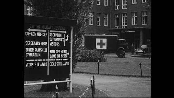Bundeswehrmobil mit Ärtzekreuz fährt vor einem Kasernengebäude (Archivbild)  