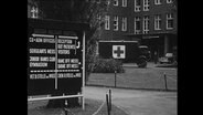 Bundeswehrmobil mit Ärtzekreuz fährt vor einem Kasernengebäude (Archivbild)  