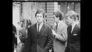 Eine Gruppe modisch gekleideter junger Männer vor einem Ladengeschäft  