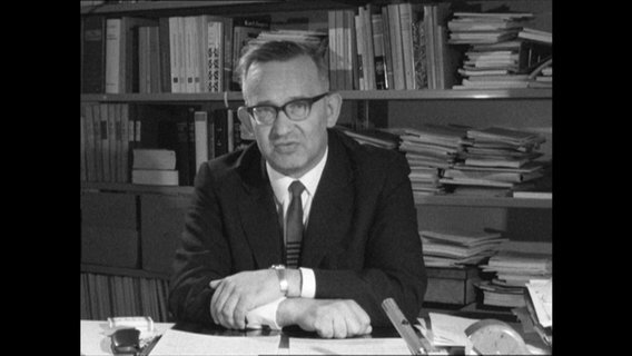 Professor Ridder sitzt vor einem Bücherregal.  