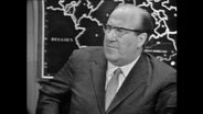 Franz Meyers, Ministerpräsident von NRW sitzt vor einer Landkarte.  