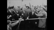 Bundesverkehrsminister Seebohm steht in einer Menschenmenge und schneidet ein Band durch (Archiv-Bild).  