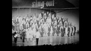 Die Gesangsgruppe "Sing out Deutschland" steht auf einer Bühne.  