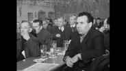 Männer sitzen bei einem Treffen der NPD an einem Tisch.  