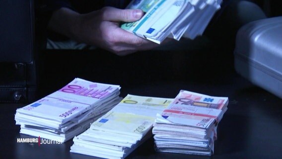 Nahaufnahme von Geldbündeln mit Euroscheinen. Die Hände einer unbekannten Person halten 100-Euroscheine (nachgestellte Szene).  