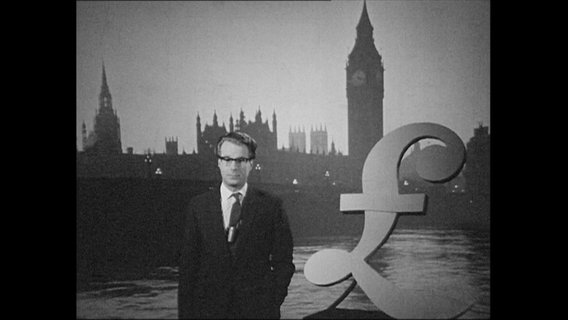 Ein Reporter steht vor dem Symbol des britischen Pfund. © Screenshot 