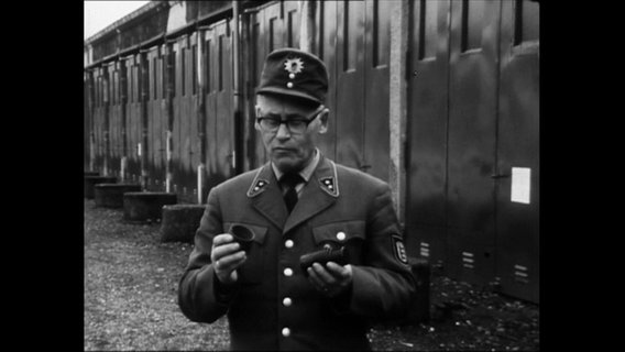 Ein Polizist in Uniform hält eine Handgranate in den Händen.  