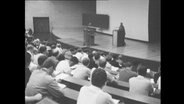 Studenten sitzen während einer Vorlesung in einem Hörsaal.  