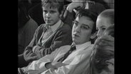 Drei Schüler sitzen in einem Hörsaal.  