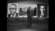 Sebastian Haffner steht vor den Bildern Schröders, Heinemanns und des Bonner Palais Schaumburg.  