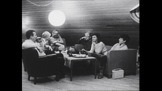 Sechs Mitglieder der Großfamilie sitzen im Wohnzimmer  