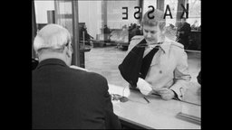 Ein Mann mit einem Gipsarms steht am Kassenschalter einer Bank (Archivbild)  