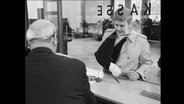 Ein Mann mit einem Gipsarms steht am Kassenschalter einer Bank (Archivbild)  