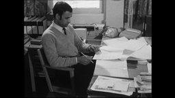 Ein Friedensforscher sitzt an einem Schreibtisch vor Papieren  