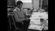Ein Friedensforscher sitzt an einem Schreibtisch vor Papieren  