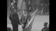 Ein Mann im ANzug trägt eine Flagge in der Hand  