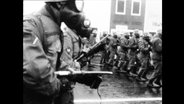 Soldaten mit Gasmasken und Gewehren laufen in einer Reihe  
