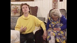 Eine jüngere und eine ältere Frau sitzen nebeneinander auf Sesseln.  