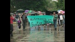Teilnehmer eines Trauermarschs, die das Banner "Wir trauern und Guter Marx" halten.  