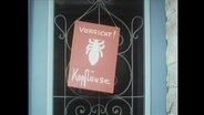 Ein rotes Schild mit der Aufschrift "Vorsicht Kopfläuse" hängt an einer Tür.  