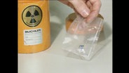 Eine Hand hält eine Plastiktüte mit illegal geschmuggeltem Plutonium.  