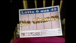 Ein inszenierter Lottoschein mit einem großen goldenen Schiftzug "Die Chance"  