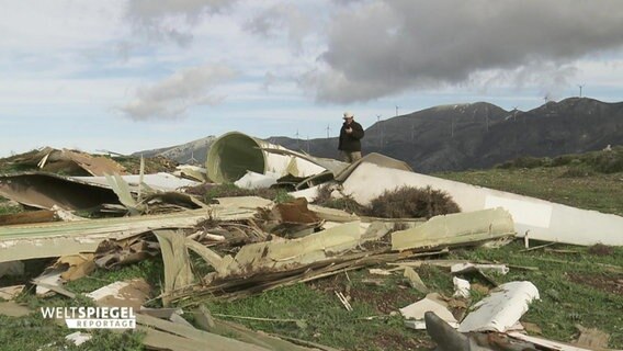 In Griechenland steht ein Mann über den Trümmern einer Windkraftanlage.  