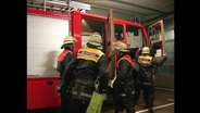 Feuerwehrmänner steigen in ein Löschfahrzeug.  