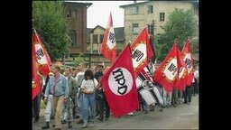 Rechte laufen mit roten NPD-Fahnen durch eine Straße (Archivbild).  