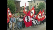 Rechte laufen mit roten NPD-Fahnen durch eine Straße (Archivbild).  