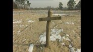 Ein Holzkreuz auf einem winterlichen Feld  
