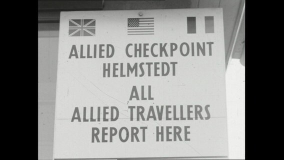 Schriftzug auf einem Schile "Allied Checkpoint Helmstedt" mit britischer, französischer und US-Flagge (1964)  