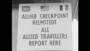 Schriftzug auf einem Schile "Allied Checkpoint Helmstedt" mit britischer, französischer und US-Flagge (1964)  