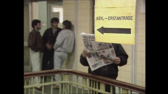 In einem Treppenhaus hängt ein Zettel mit der Aufschrift "Asyl-Erstanträge"  