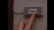 Ein Finger drückt auf das Klingelschild eines Frauenhauses  