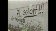 Ein Graffiti mit dem Inhalt "Zusammenlegung jetzt!"  