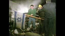 Menschen stellen nach einem Bobemangriff eine Israelflagge in den Trümmern auf  